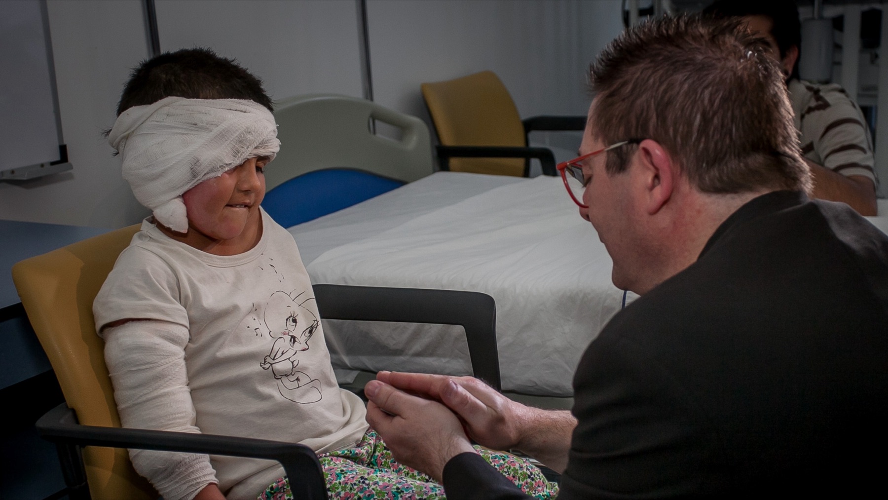 Artista conversa con un niño durante una visita al hospital