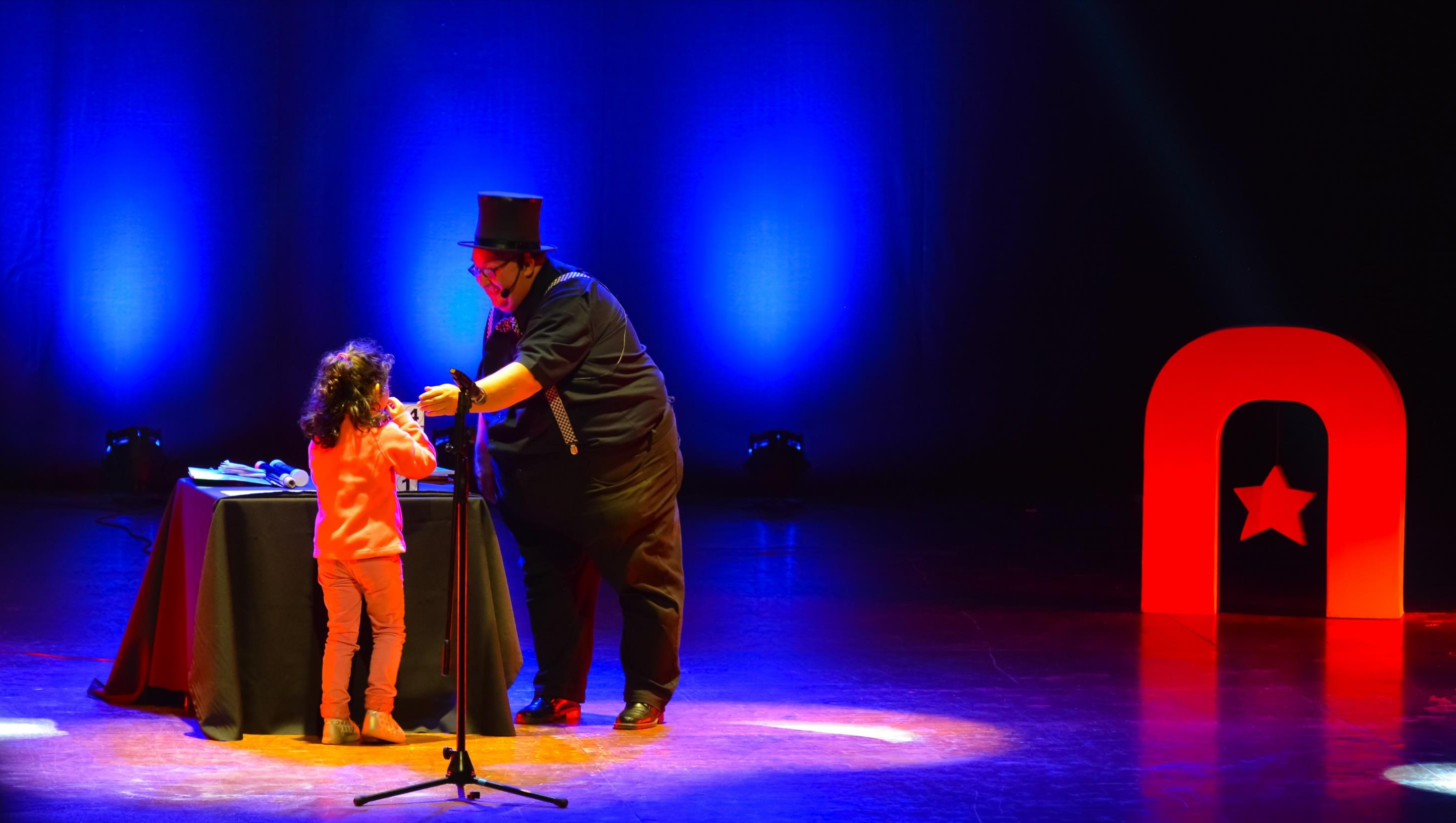 Artista de Atacamagica Kusiy comparte un número de ilusionismo con una niña en el escenario
