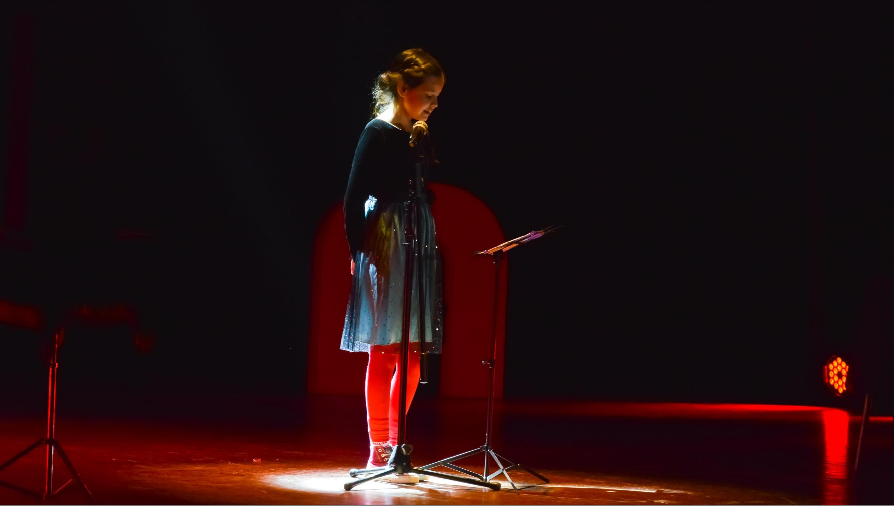 Niña participa frente al micrófono durante una función de Atacamagica Kusiy