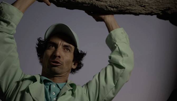 Character with green wardrobe under a dark structure
